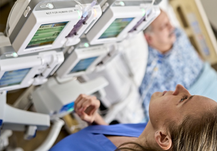 hcp monitoring infusion system pumps next to patient in bed